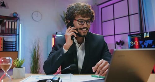 Man Talks on Phone and Types at Desk
