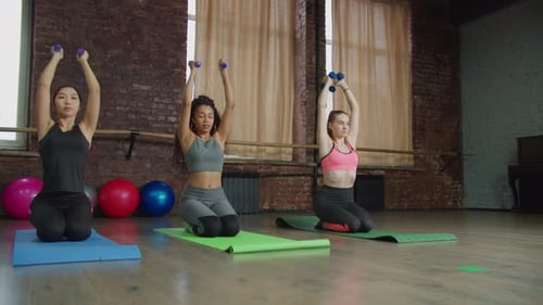Women on Knees Doing Arm Exercises with Weights