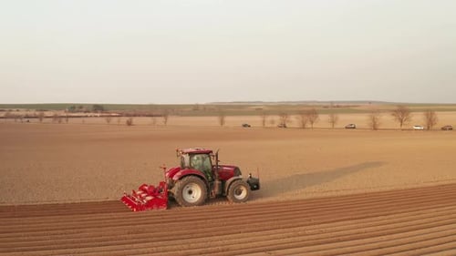 Aerial View of Red Farming Tractor Seeding Wheat at the Field