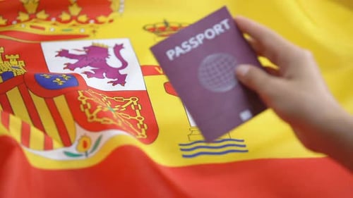 Passport on Flag of Spain for Travel Concept