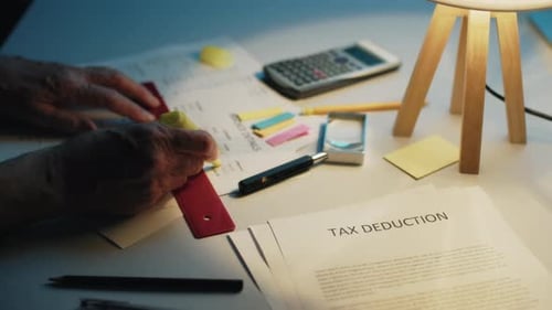 Man is Doing the Tax Deduction of Taxes on the Table at Home