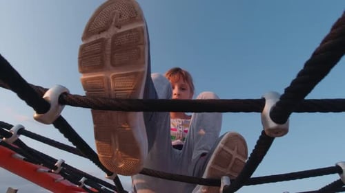 Child Climbing on Rope Structure at Playground