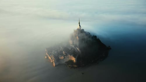 Epic Aerial Shot of Ethereal Mont Saint Michel Island Castle Covered with Amazing Sunrise Fog Clouds