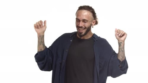 Rapaz hippie despreocupado com tatuagens de barba no rosto e no corpo, dançando, despreocupado e sorrindo, feliz e curtindo