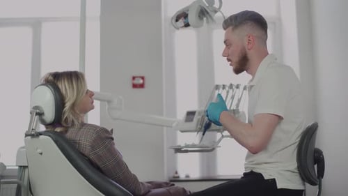 The male dentist explains to the patient the treatment plan at the dental clinic. The work of a dent
