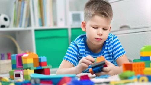 Young Boy Plays with Colorful Building Blocks at Home