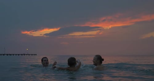 At sunset mother, father with their son swimming in sea of city Perea, Greece
