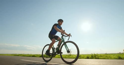 A Sportsman on a Bicycle is Slowly Riding Along the Track