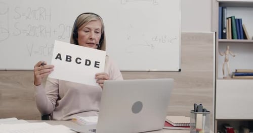 Crop View of Female Teacher Talking and Holding Paper Sheet with Letters While Looking To Camera