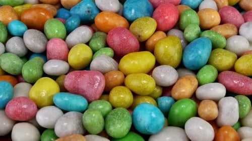 Stapel mit vielen runden Kaubonbons Dragee in mehrfarbiger Glasur, langsam auf Drehteller rotieren