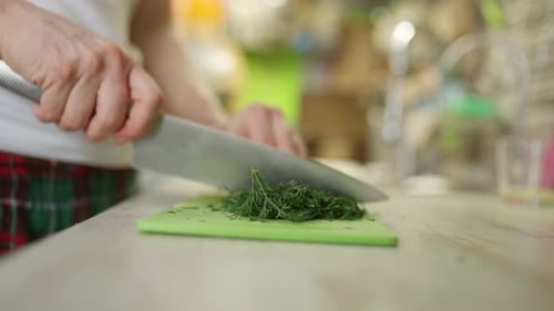 Crop Man hackt Kräuter auf Schneidebrett in der Küche