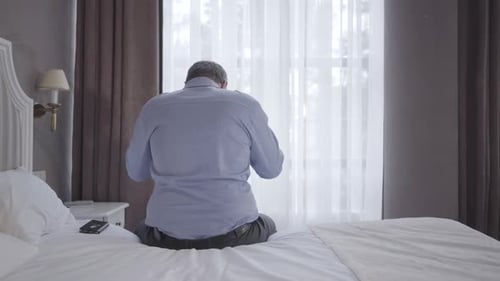 Vue arrière d'un homme adulte debout du lit et partant. Un homme d'affaires caucasien sérieux s'entraîne