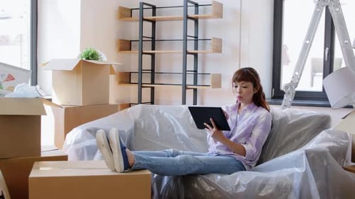 Young Woman Uses Tablet in Packed Moving Room