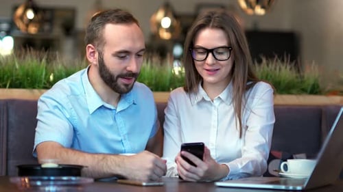 Woman Showing Phone to Man in Modern Restaurant