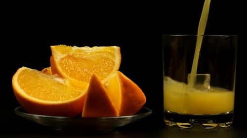 Pouring Orange Juice into Glass with Ice Cubes