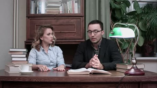 Woman and Man Discussing Over Books at Desk
