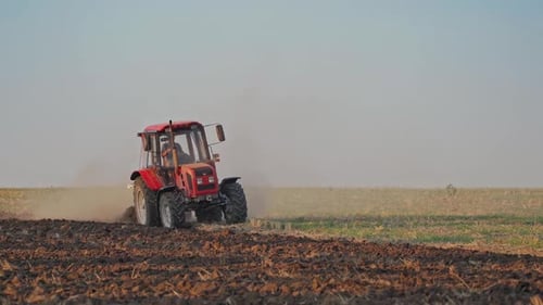 Red Tractor Tills Soil in Rural Farmland