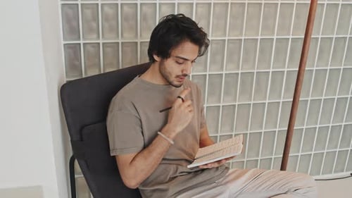 Young Man Writing in Notebook at Home