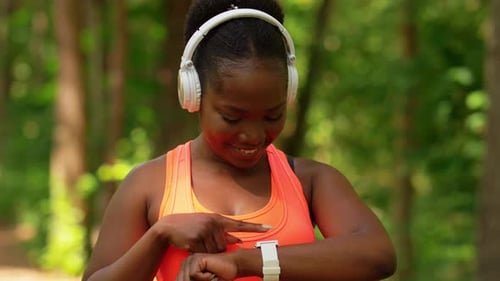 Woman Checks Smartwatch in a Forest