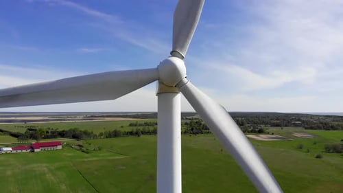 Aerial Move Up: Close View of Windmill Rotating Blades on Blue Sky