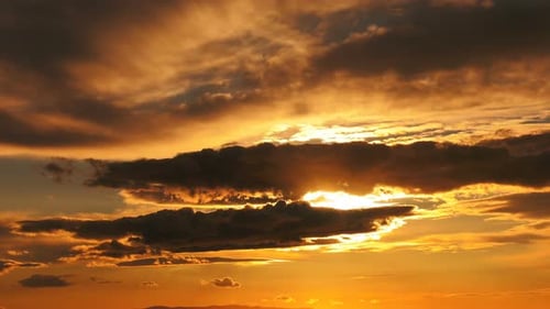 Dunkle glatte Wolken im orangefarbenen Sonnenuntergang