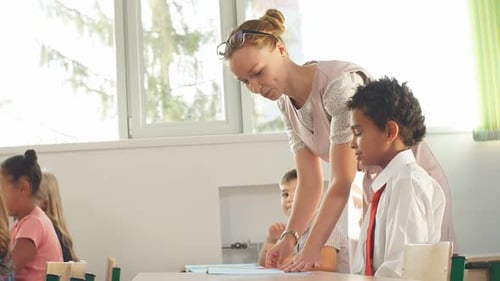 Teacher Helping Kids with Their Homework in Classroom at School