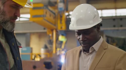 Senior Multiethnic Engineers Discussing Work in Factory