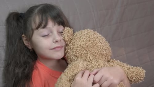Little Girl Hugging Teddy Bear on Sofa