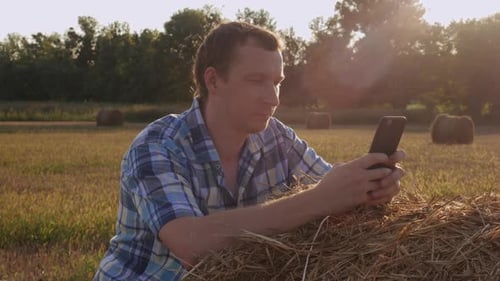 Farmer Checks Phone in Golden Rural Field
