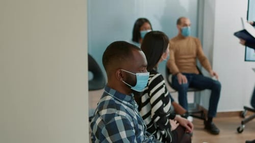 Adults in face masks are handed clipboards