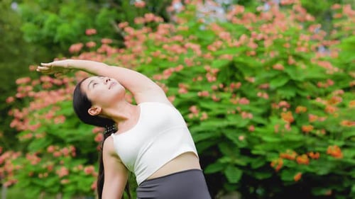 Young asian woman practicing yoga in garden.