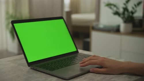 Caucasian Woman's Hand Swiping on a Laptop Touchpad with a Chroma Key Green Screen on It