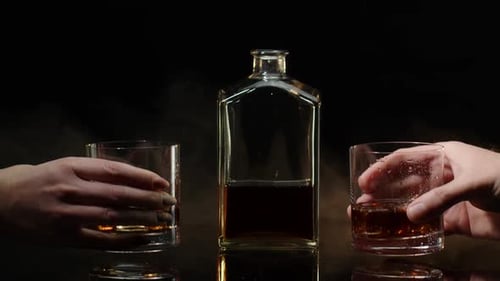 Deux mains avec des verres de whisky au cognac avec des glaçons faisant des toasts sur fond noir