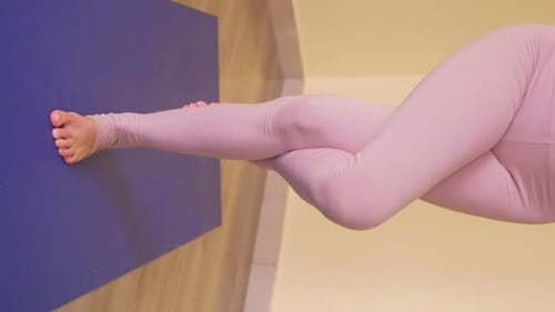 Fille mince en tenue de sport faisant de l'exercice de yoga Garudasana ou Eagle pose pieds nus sur un tapis dans le sport