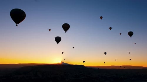 Hot Air Balloons Floating Over Mountains at Sunrise