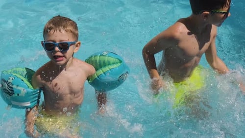 Active Caucasian Boys playing in Swimming pool, splasing water in Slow motion