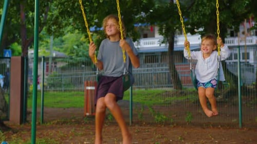 Brother and Sister are Having Fun on the Swing