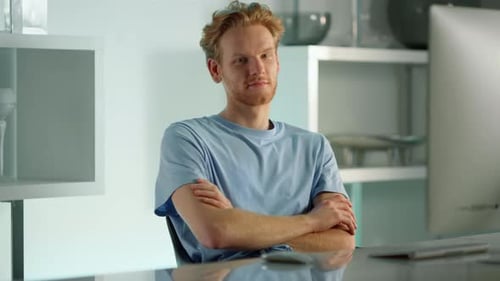 Smiling Man Sits at Desk With Arms Crossed