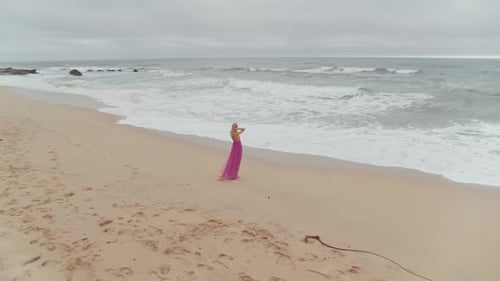 Woman In A Dress Wandering On The Beach