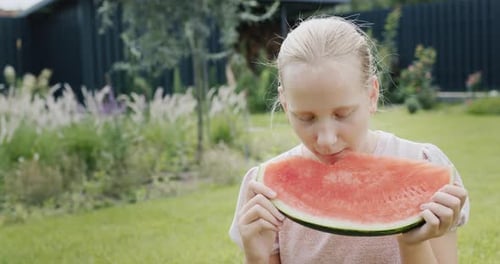 Girl Enjoys Watermelon Slice in Summer Garden