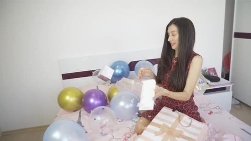 Woman Opens Birthday Card Surrounded by Balloons