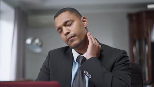 Portrait of Focused Young Man Having Sudden Neck Pain Sitting at Laptop in Home Office