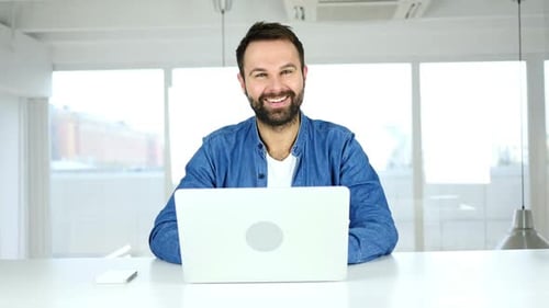 Thumbs Up By Man Sitting in Office Looking at Camera