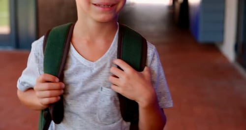 Young Boy Smiling with Backpack in School Corridor