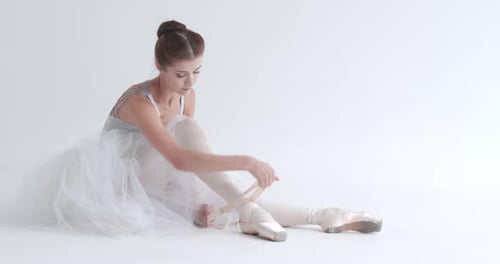 Ballerina Tying Her Ballet Slippers in Studio
