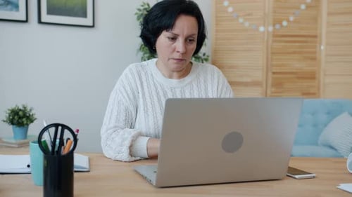 Stressed Woman Working with Laptop Typing Then Touching Head Feeling Headache at Home