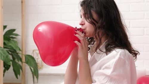 Woman Inflating a Red Heart Shaped Balloon
