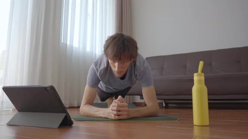 Adult Does Plank at Home Following Tablet