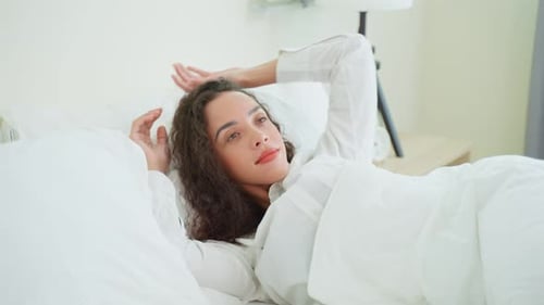 Young Woman Waking up and Stretching in Bed
