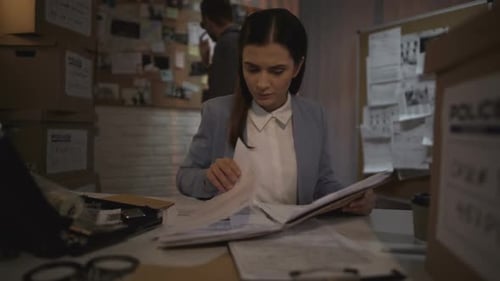 Female Detective Reviews Files in Police Office